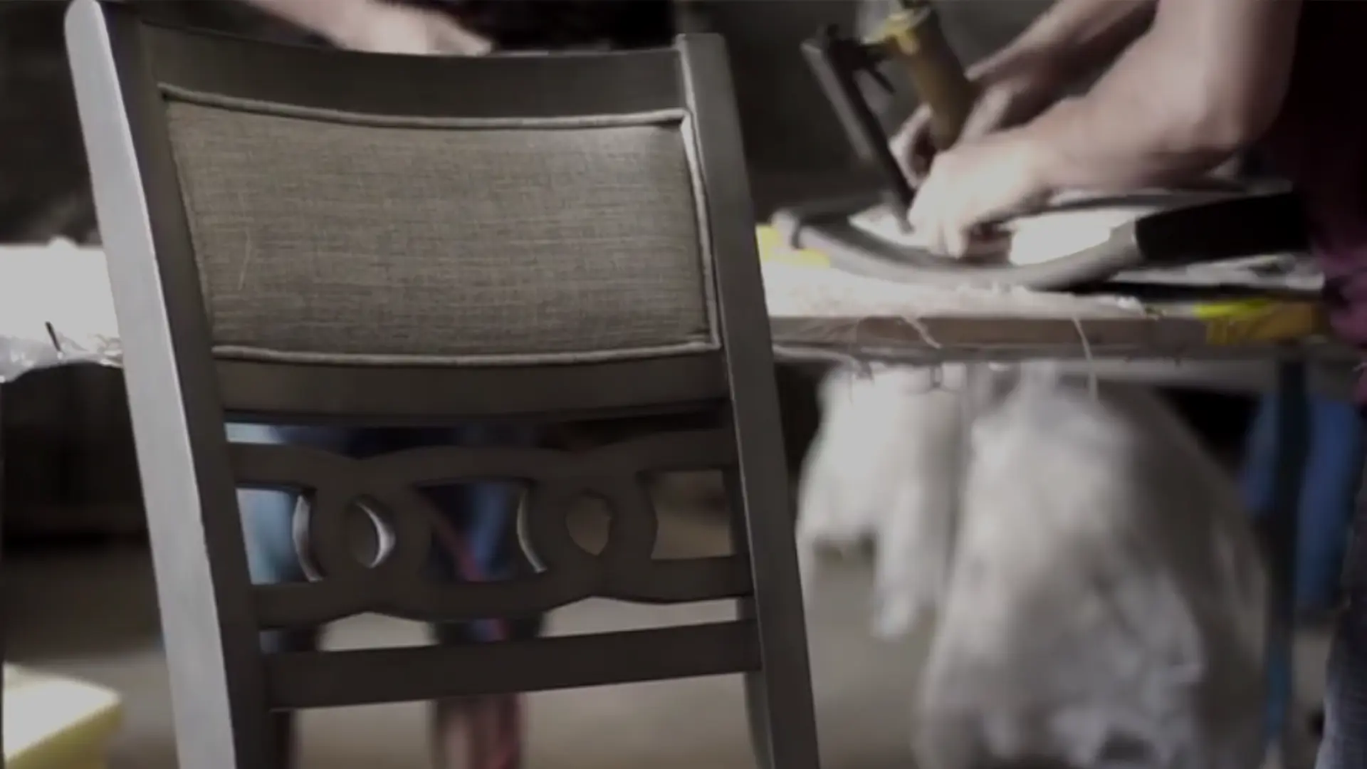 Close-up of New Classic Furniture manufacturing process showing an artisan upholstering a dining chair.